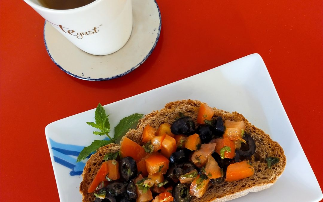 Tomate, cebolla, aceitunas negras, albahaca y cilantro sobre pan de espelta integral con infusión de ratafía fresca-desayuno